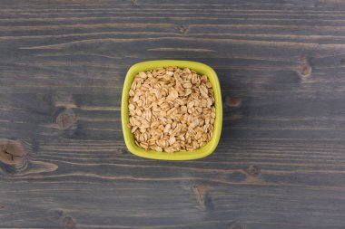 Yulaf veya yulaf gevreği kapta ahşap arka plan üzerinde yuvarlandı. Sağlıklı yaşam tarzı, sağlıklı beslenme kavramı. Üstten görünüm 