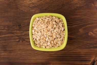 Yulaf veya yulaf gevreği kapta ahşap arka plan üzerinde yuvarlandı. Sağlıklı yaşam tarzı, sağlıklı beslenme kavramı. Üstten görünüm 