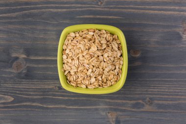 Yulaf veya yulaf gevreği kapta ahşap arka plan üzerinde yuvarlandı. Sağlıklı yaşam tarzı, sağlıklı beslenme kavramı. Üstten görünüm 