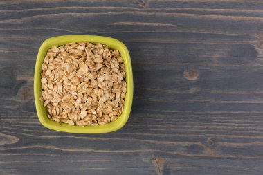 Yulaf veya yulaf gevreği kapta ahşap arka plan üzerinde yuvarlandı. Sağlıklı yaşam tarzı, sağlıklı beslenme kavramı. Üstten görünüm