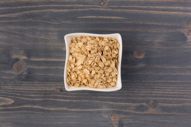 Yulaf veya yulaf gevreği kapta ahşap arka plan üzerinde yuvarlandı. Sağlıklı yaşam tarzı, sağlıklı beslenme kavramı. Üstten görünüm 