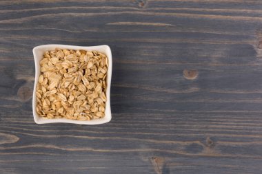 Yulaf veya yulaf gevreği kapta ahşap arka plan üzerinde yuvarlandı. Sağlıklı yaşam tarzı, sağlıklı beslenme kavramı. Üstten görünüm 