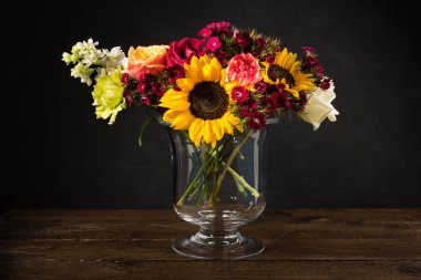 Karanlık bir arka plan üzerinde bir vazoda beyaz sarı ve kırmızı çiçekler Buket