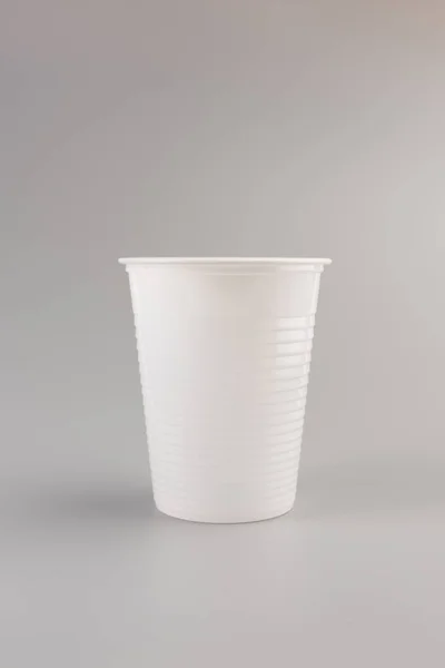 灰色の背景に分離された丸い白いプラスチック ガラス — ストック写真