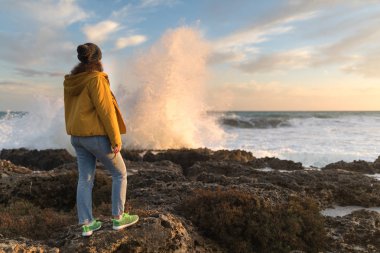 Puglia boş plaj kış döneminde, Güney İtalya duran yalnız kadın. Güçlü dalgalar kayalar isabet