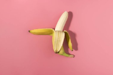 Taze soyulmuş muz kontrast gölgeler, düz pembe arka plan üzerinde yatıyordu