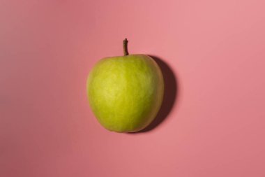 Kontrast gölgeler ile pembe arka plan üzerinde izole yeşil lezzetli elma dilimli