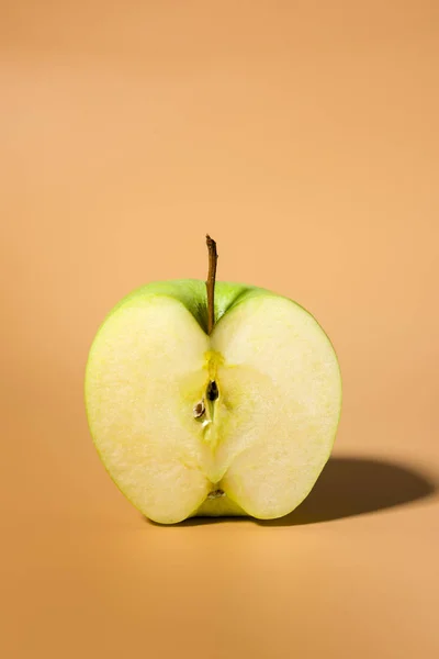 影のコントラスト オレンジ色の背景に分離された緑のおいしいリンゴをスライス — ストック写真