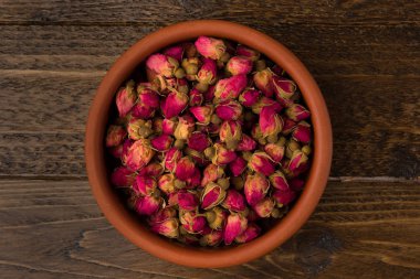 ahşap arka plan üzerinde üstten görünüm izole bir toprak kap içinde çay gül tomurcukları