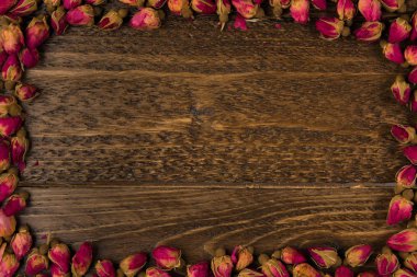 ahşap arka plan, üstten görünüm üzerinde kuru gül goncası çerçevesinde