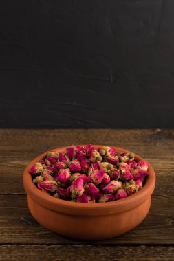 siyah arka plan üzerine ahşap masa üzerinde izole bir toprak kap içinde çay gül tomurcukları