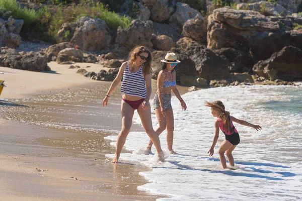 Mother with kid play with water, runing on the beach