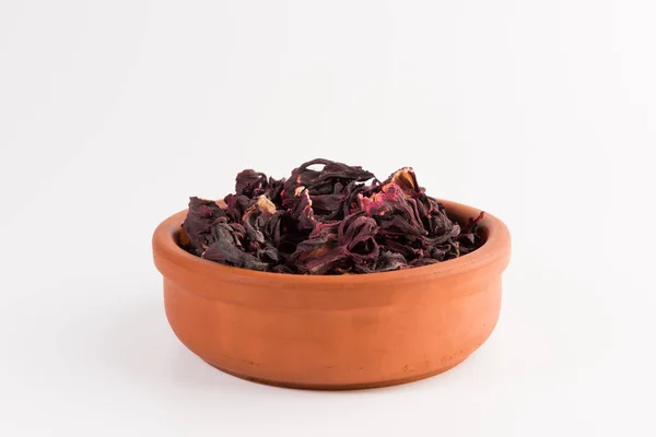 petals of dry hibiscus tea  in the clay pot isolated on white background