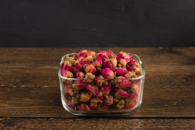 bir cam kase siyah arka plan üzerine ahşap masa üzerinde izole içme Tea gül tomurcukları