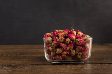 bir cam kase siyah arka plan üzerine ahşap masa üzerinde izole içme Tea gül tomurcukları