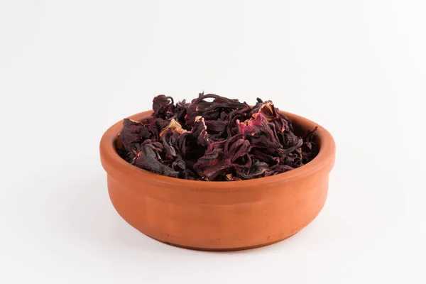 petals of dry hibiscus tea  in the clay pot isolated on white background
