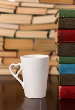 Kupası ve ahşap bir masa üzerine pek çok kitap