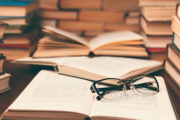 Açık kitap ve eğitim arka plan için daha sonra tekrar okul kavramı bulanık odak ile kütüphane odada ahşap masa üzerinde gözlük