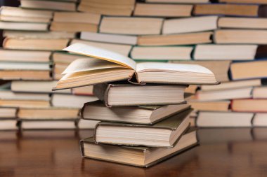 Tahta masanın üzerinde bir yığın kitap var.