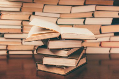 Tahta masanın üzerinde bir yığın kitap var.