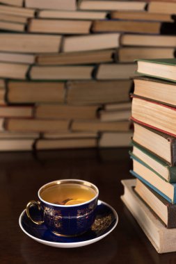fincan çay ve bir ahşap masa üzerinde pek çok kitap