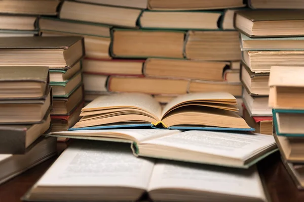 Eğitim kavramı açık kitap ve masanın üstünde defter ile öğrenme. Kitap okuma Resepsiyon ve gözlük kitap rafı arka planda yığınları yığını