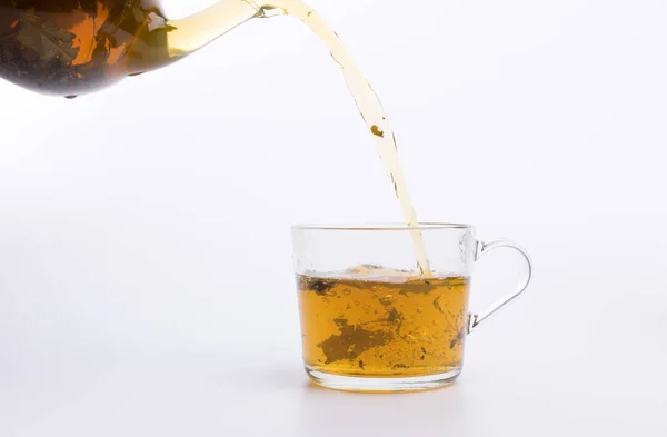 白い背景で隔離のカップにお茶を注ぐガラスのティーポット — ストック写真