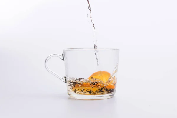 水倒进玻璃杯与红茶和柠檬隔离在白色背景 — 图库照片
