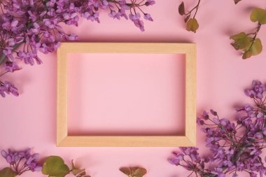 Çiçek kompozisyon. Mor çiçekler, yapraklar ve pastel pembe arka plan üzerinde fotoğraf çerçevelemek. Düz yatıyordu, en iyi görünüm, kopya alanı