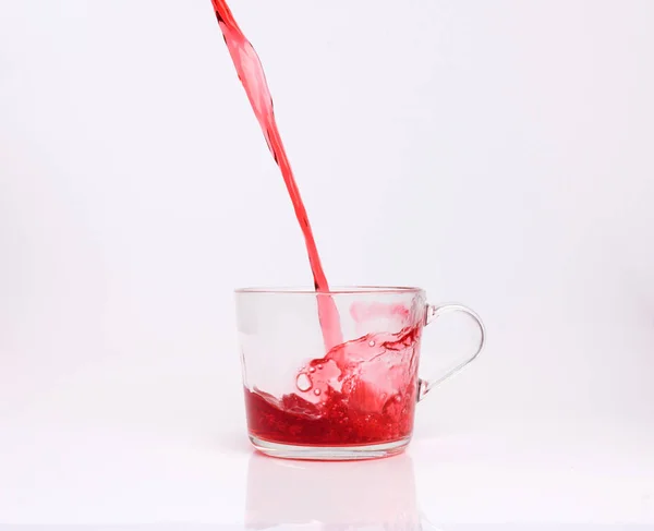 Fruit tea pouring in the cup isolated on white background