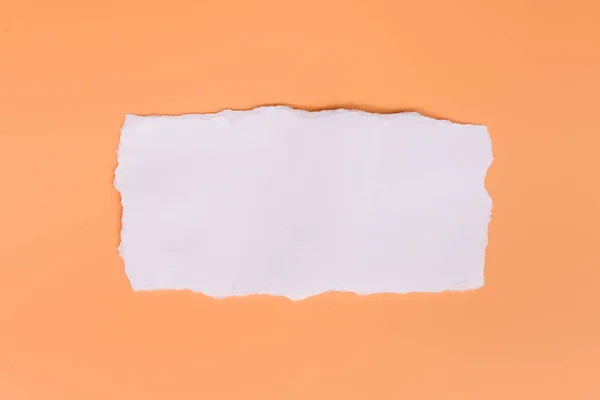 オレンジ色の背景に白い破れた紙の一部 — ストック写真