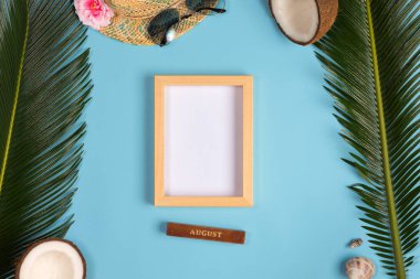 Fotoğraf çerçevesi, yeşil yapraklar, mavi pastel arka plan üzerinde şapka ve güneş gözlüğü ile şık yaz kompozisyon. Kopyalama alanı ile resim maket