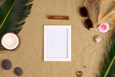 Fotoğraf çerçevesi, yeşil yaprakları, şapka ve kum arka plan üzerinde güneş gözlüğü ile şık yaz kompozisyon. Kopya alanı ile sanat mockup