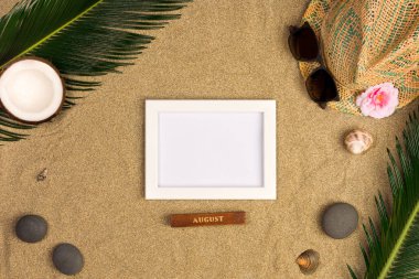 Fotoğraf çerçevesi, yeşil yaprakları, şapka ve kum arka plan üzerinde güneş gözlüğü ile şık yaz kompozisyon. Kopya alanı ile sanat mockup