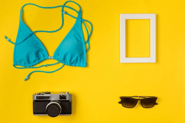 swimsuit, frame, camera, sunglasses on a yellow background, top view