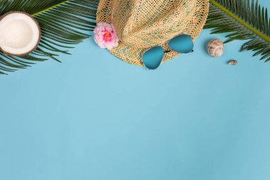 Pastel mavi renk arka plan üzerinde güneş gözlüğü, palmiye yaprakları ve panama şapka ile Yaratıcı Düz yatıyordu moda tarzı