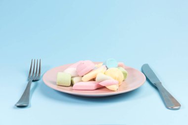 Mavi arka plan üzerinde izole marshmallow, çatal, bıçak ile Plaka.