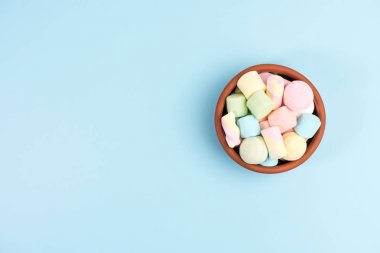 Yuvarlak bir kapta Marshmallows, mavi arka plan üzerinde izole. Üstte görüntü.