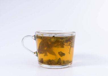 Beyaz arka planda izole şeffaf bir bardak yeşil bitkisel çay