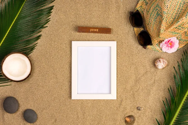 Fotoğraf çerçevesi, yeşil yaprakları, şapka ve kum arka plan üzerinde güneş gözlüğü ile şık yaz kompozisyon. Kopya alanı ile sanat mockup