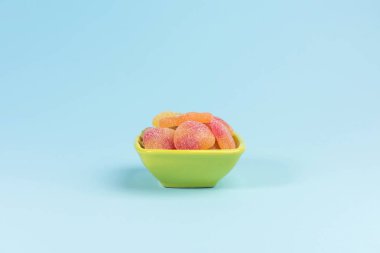 Mavi arka plan üzerinde sakızlı şekerler ile küçük kase.