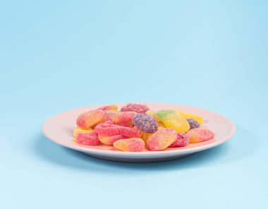 Mavi arka plan üzerinde izole sakızlı şekerler ile pembe plaka.