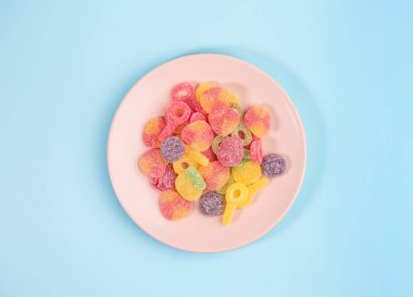 Mavi arka planda sakızlı şekerli pembe tabak. Üstte görüntü.