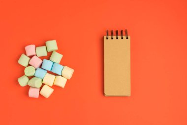 Marshmallow ve not defteri ile Mercan kağıt arka plan. Metniniz için yerleştirin. Rahat tatlı arka plan