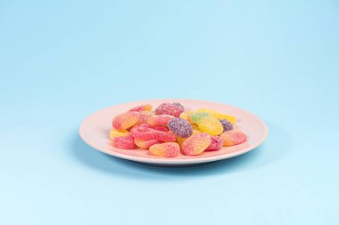 Mavi arka plan üzerinde sakızlı şekerler ile pembe plaka.