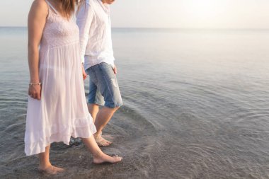 Tatil seyahat tatillerinde sahilde romantik yürüyen el ele tutuşan çift. Kopya alanı için gövde ve altın kum yakın çekim. Genç seven çift 