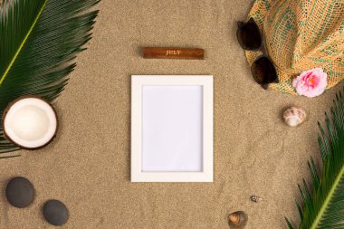 Fotoğraf çerçevesi, yeşil yaprakları, şapka ve kum arka plan üzerinde güneş gözlüğü ile şık yaz kompozisyon. Kopya alanı ile sanat mockup