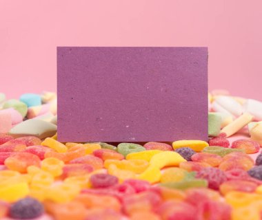 Şekerli jöle ve boş not defteri ile pembe kağıt arka plan. Metniniz için yerleştirin. Rahat tatlı arka plan