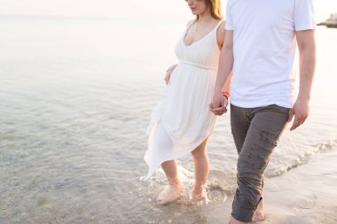 Tatil seyahat tatillerinde sahilde romantik yürüyen el ele tutuşan çift. Kopya alanı için gövde ve altın kum yakın çekim. Genç seven çift 