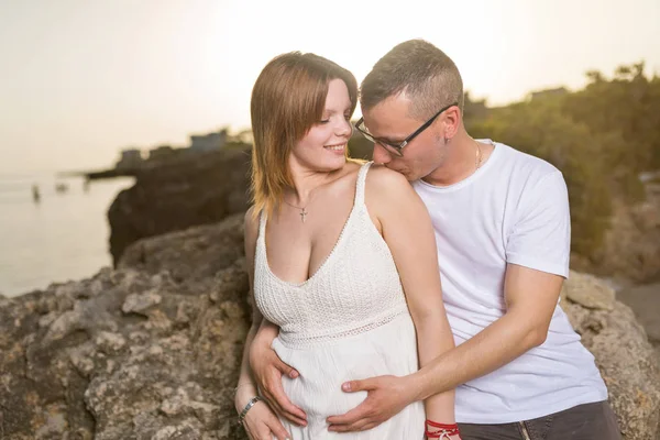 Νεαρό Ζευγάρι Έγκυος Στην Παραλία Ηλιοβασίλεμα Άνθρωπος Αγκαλιάζει Την Έγκυο — Φωτογραφία Αρχείου